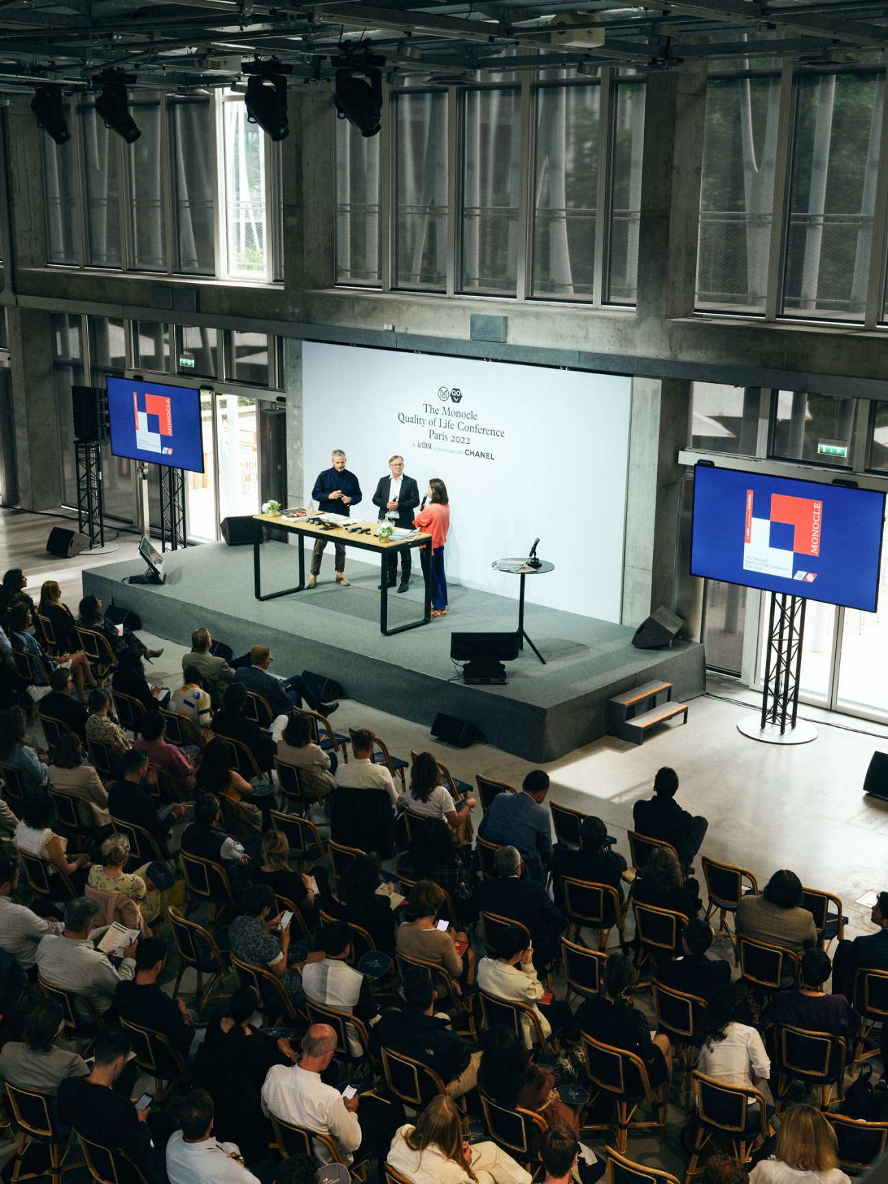 Speakers presenting at Monocle's Quality of Life Conference in Paris with audience seated below