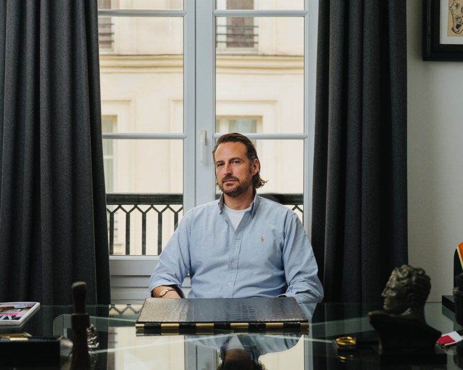 Vincent Ribat of Rue de Verneuil sitting at a glass desk in an office with large windows