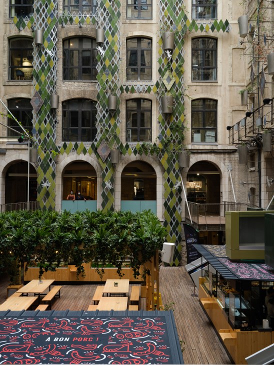 Interior courtyard of Docks Village development with ivy-covered facade and wooden seating area.