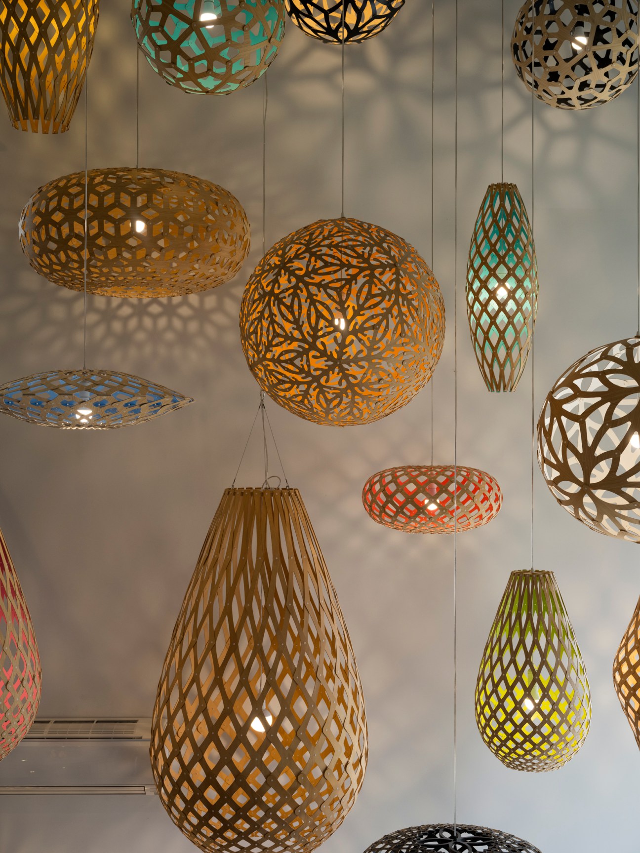 Colorful geometric pendant light fixtures by designer David Trubridge hanging from ceiling