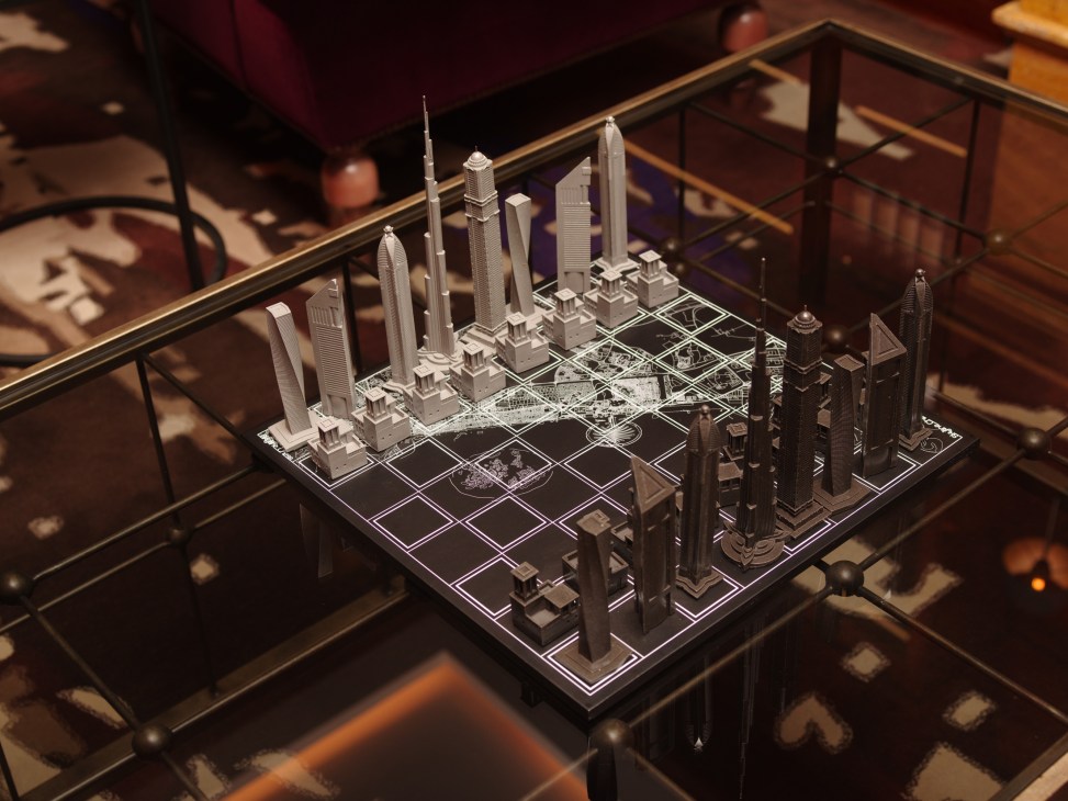A miniature architectural model of a city skyline displayed under glass on an illuminated base.