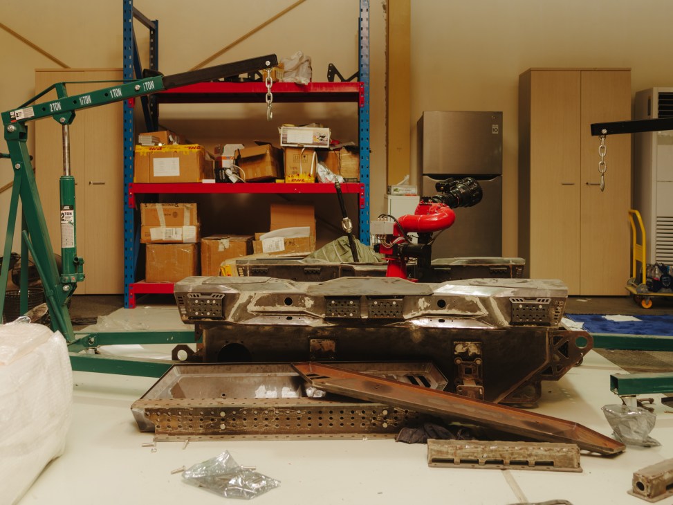 Industrial warehouse with metal aircraft components on workbench and storage shelves.