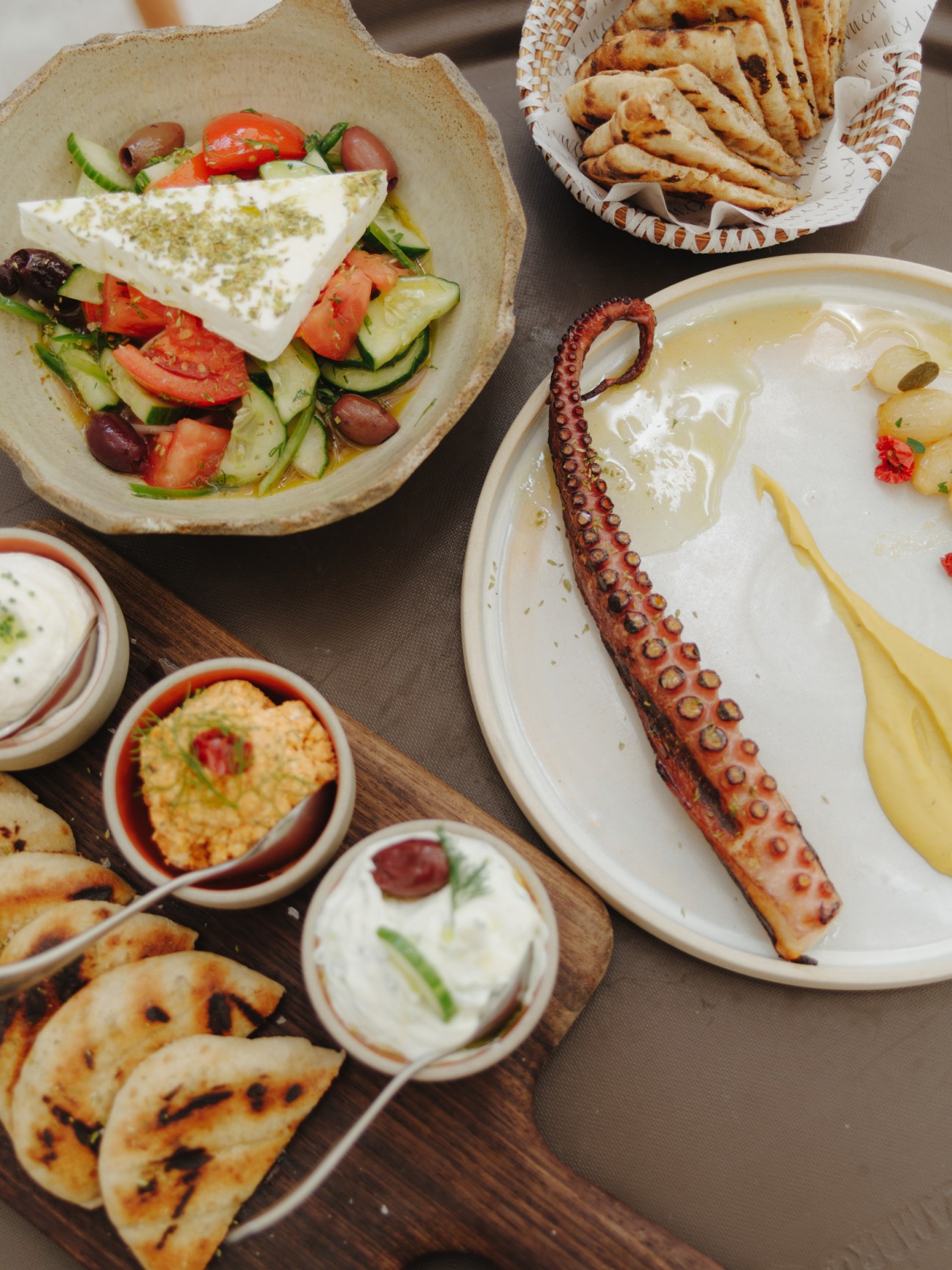 Greek dishes at Kyma beach club including salade with feta, grilled octopus, and pita bread.
