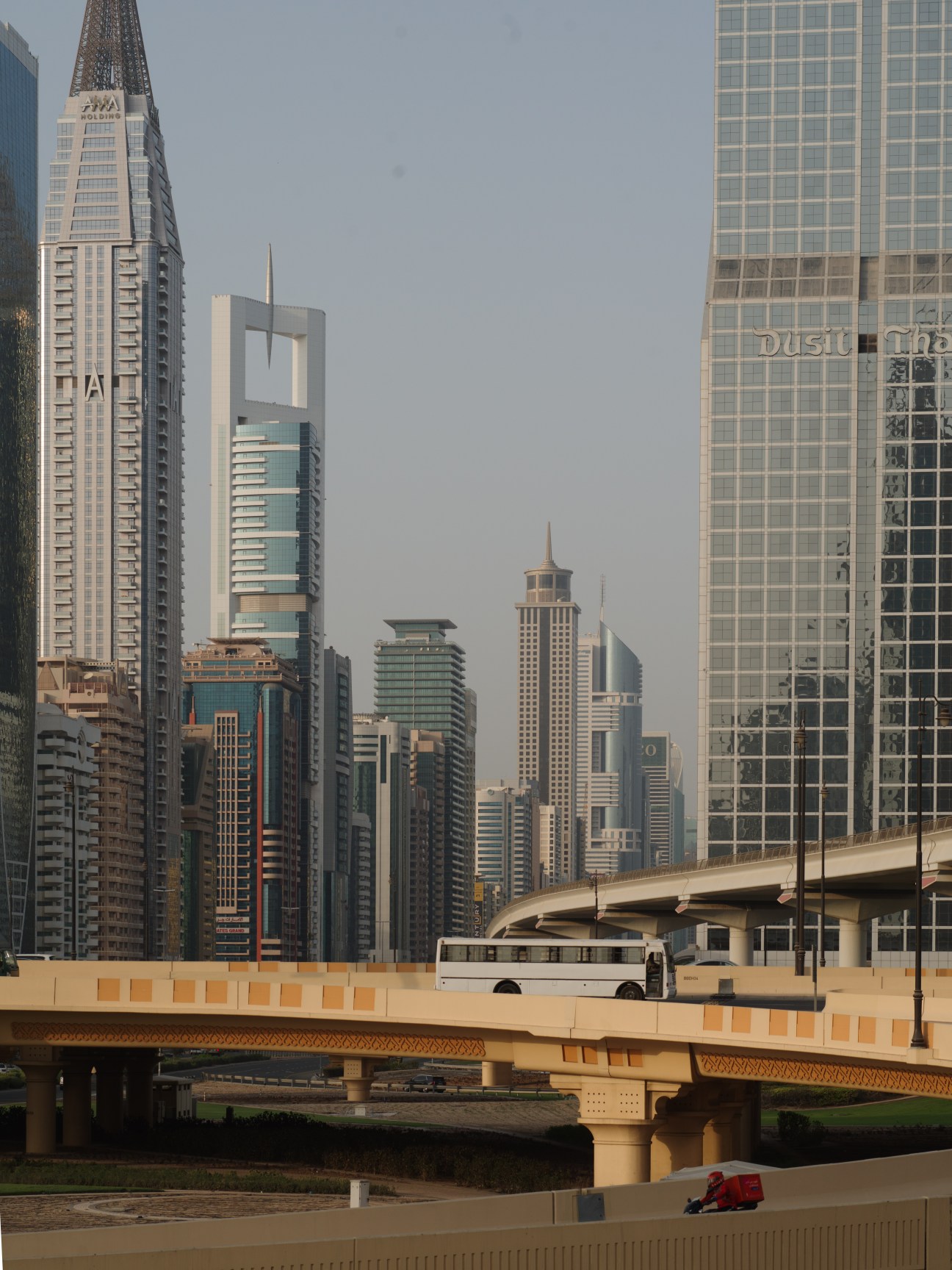 Downtown Dubai skyline with modern skyscrapers and an elevated highway with a bus.