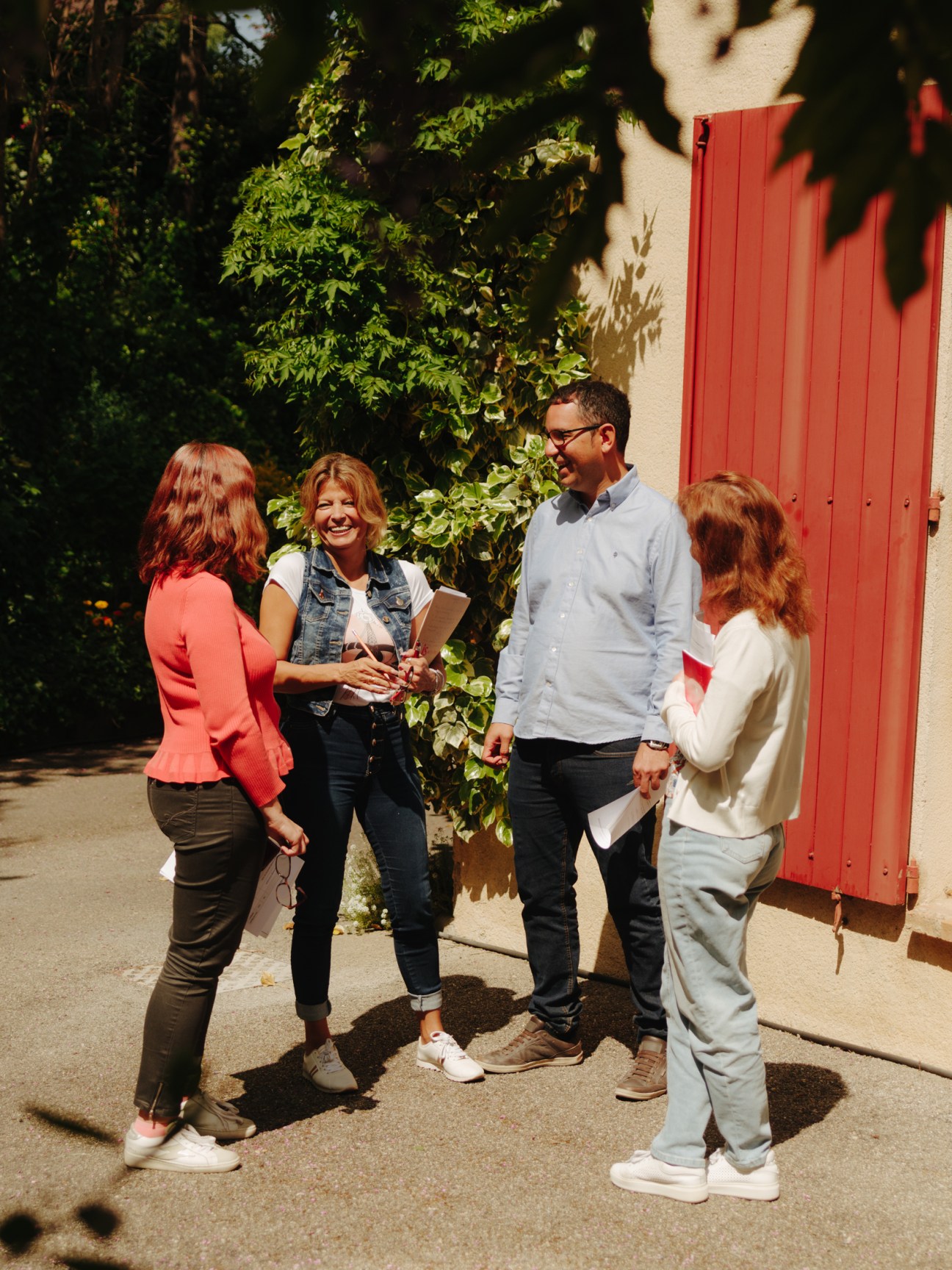 Four people having a conversation outdoors in a sunny courtyard setting