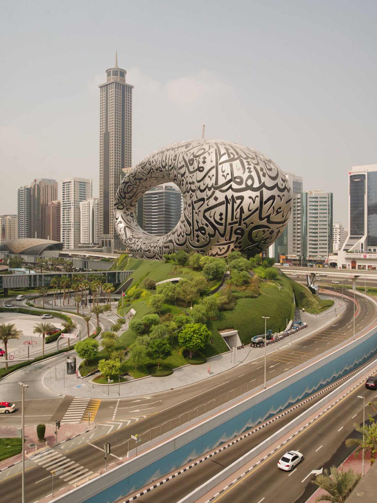 The Museum of the Future's distinctive metallic spherical structure with Arabic calligraphy sits on a verdant mound in Dubai's skyline.