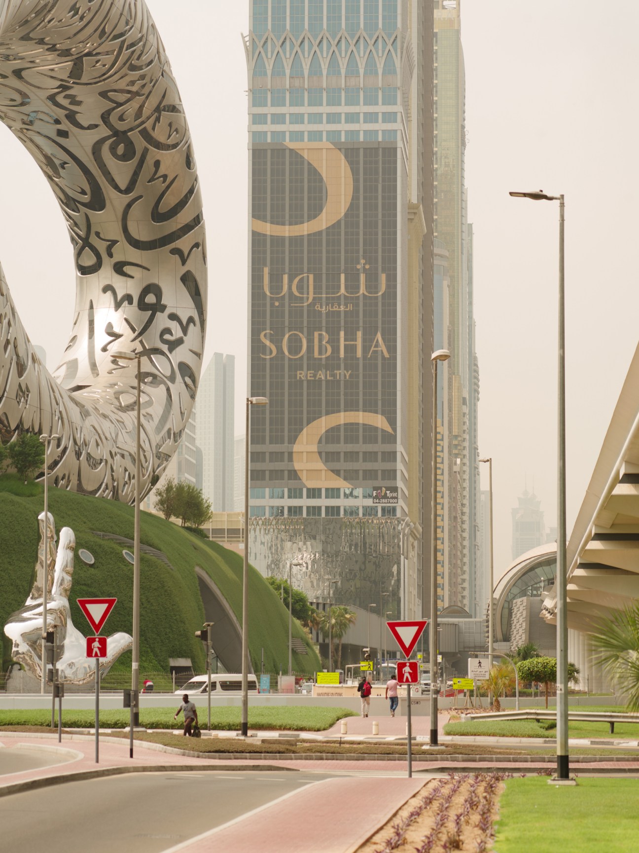 Building wrap advertisement for Sobha Realty on a Dubai skyscraper with Arabic calligraphy design.