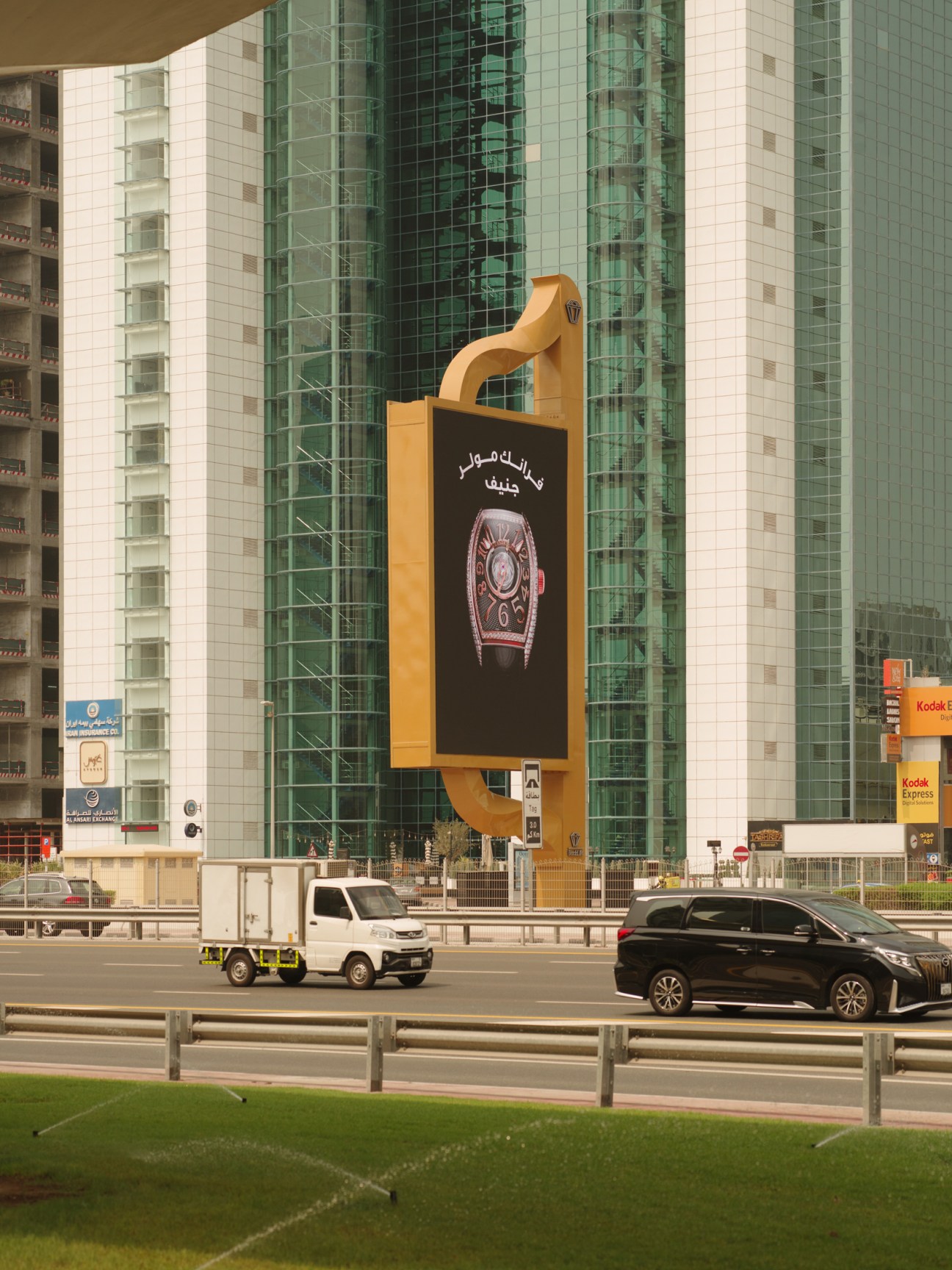 Large creative billboard shaped like a gold door handle displaying a luxury watch advertisement on a Dubai street.