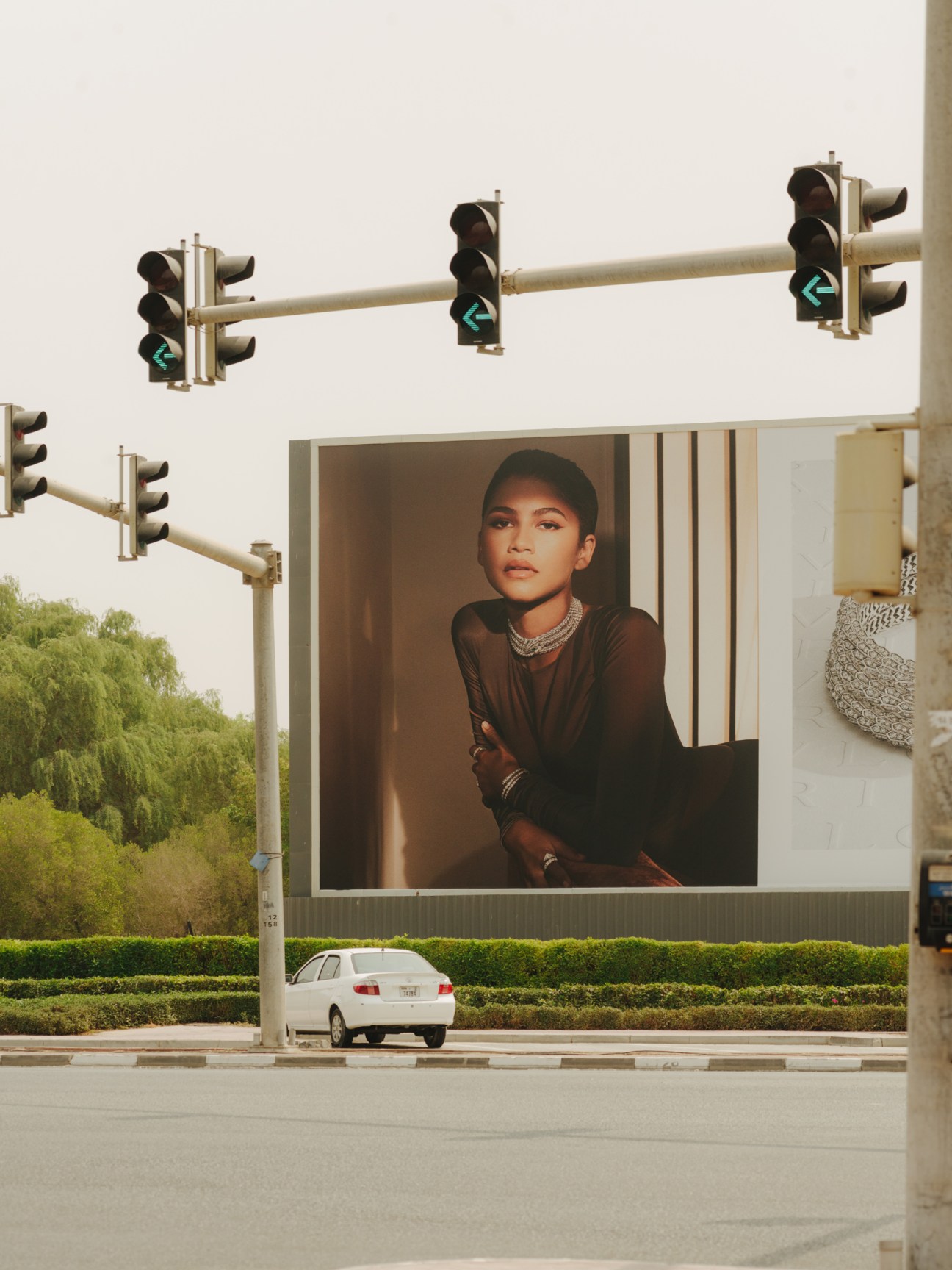 Large billboard advertisement at traffic lights showing a woman wearing jewelry against a neutral background.
