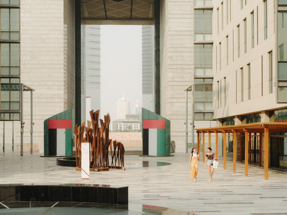 Pedestrian concourse at Dubai International Financial Centre with modern architecture, sculpture, and city views.