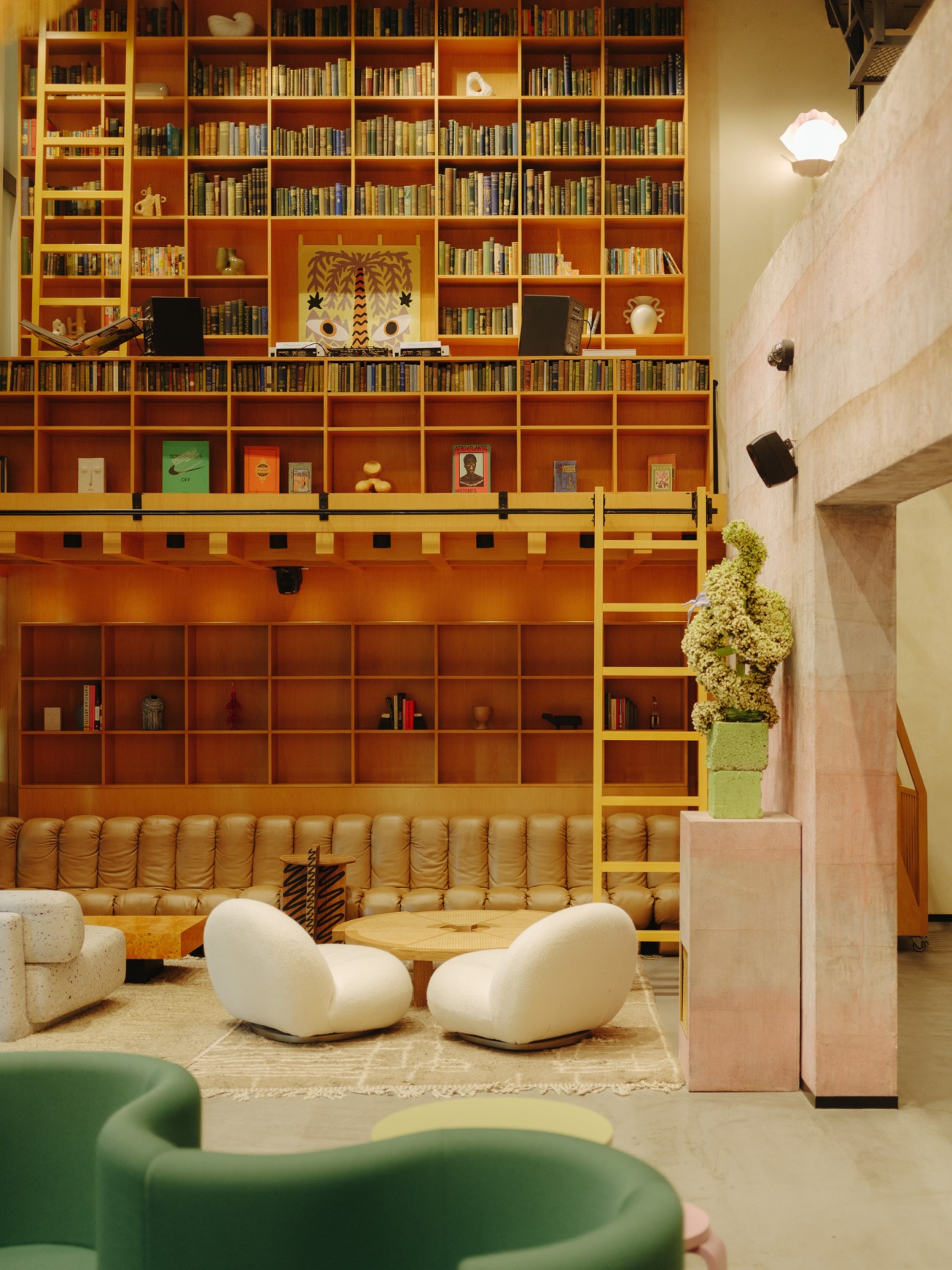 Interior of Lulu & The Beanstalk showing floor-to-ceiling orange wooden bookshelves, a tan leather banquette, and modern white seating.