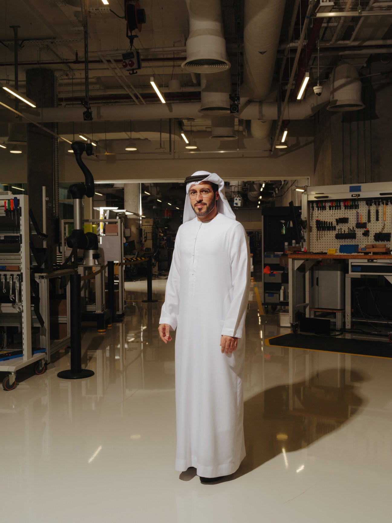 Director Khalifa Al Qama stands in Dubai Future Labs robotics facility wearing traditional white Emirati dress.