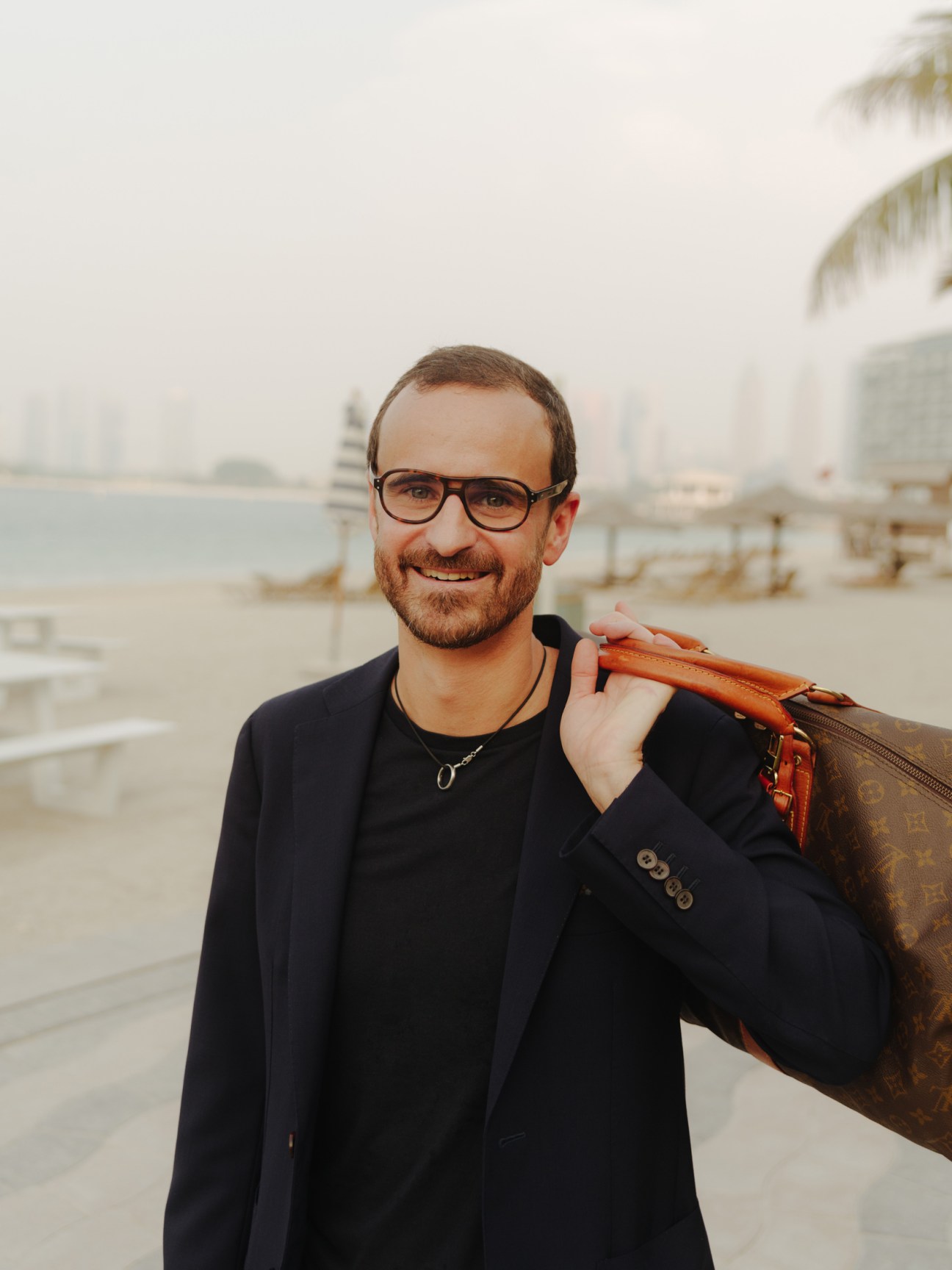Jonathan Hasson, founder of Ubqt, poses by a waterfront with a bag over his shoulder.