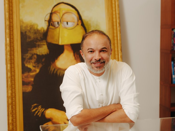 Mohammed Saeed Harib smiles at Lammtara Studio with a Freej character portrait behind him.