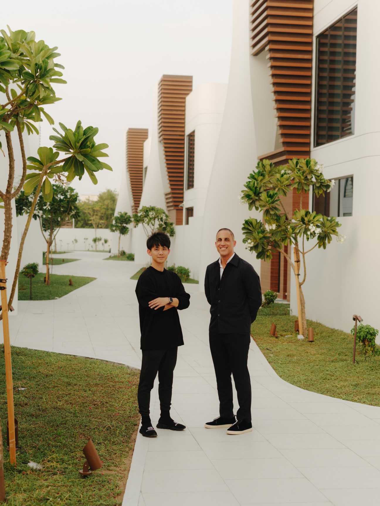 Two men stand in a modern villa courtyard with louvered balconies, young trees, and manicured lawn at The Fold in Dubai.
