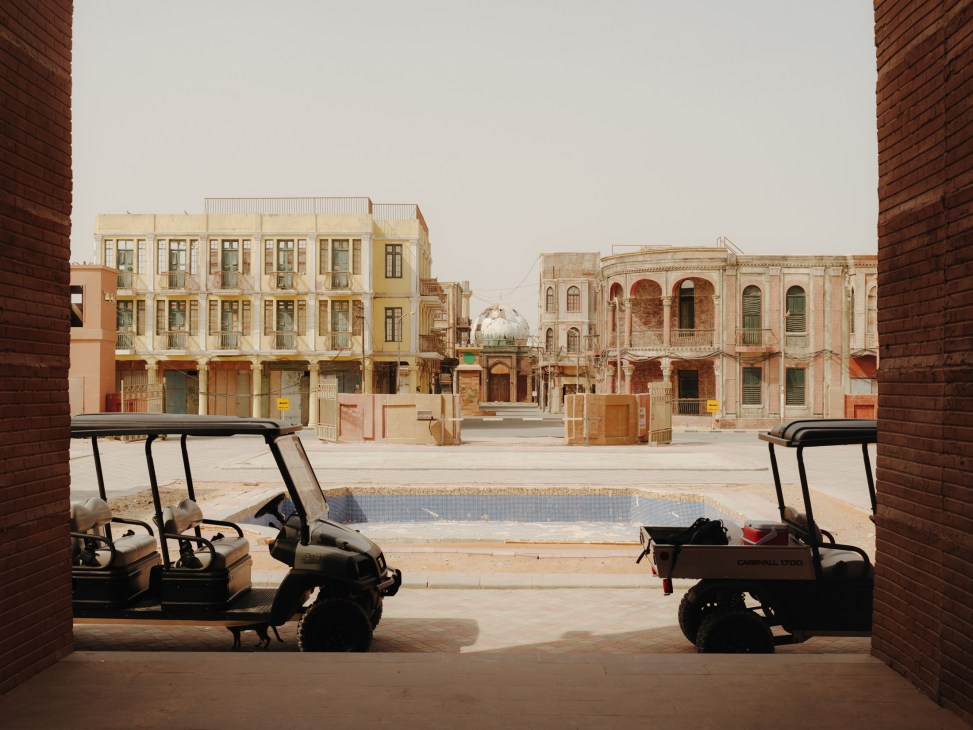Film set backlot with historic Middle Eastern architecture and parked golf carts in foreground.