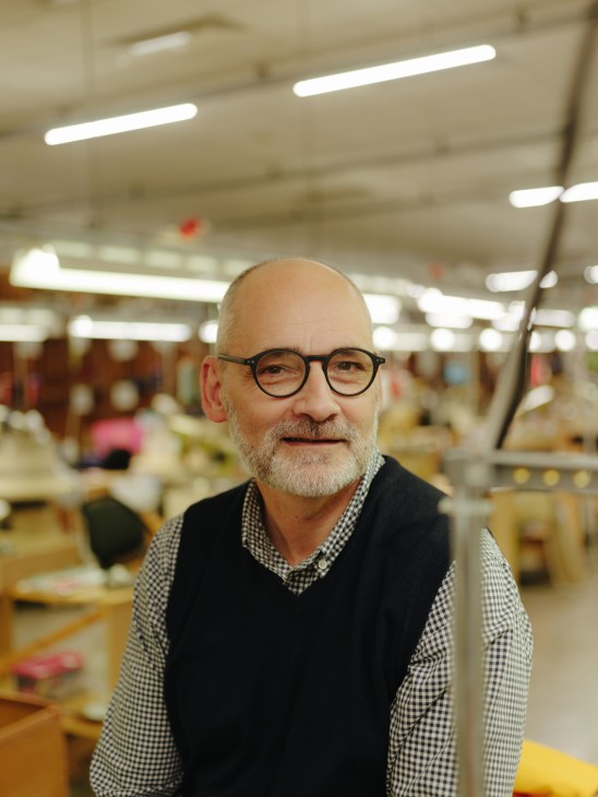 Nick Bannerman of Johnstons wearing glasses and a checkered shirt in a cashmere factory.