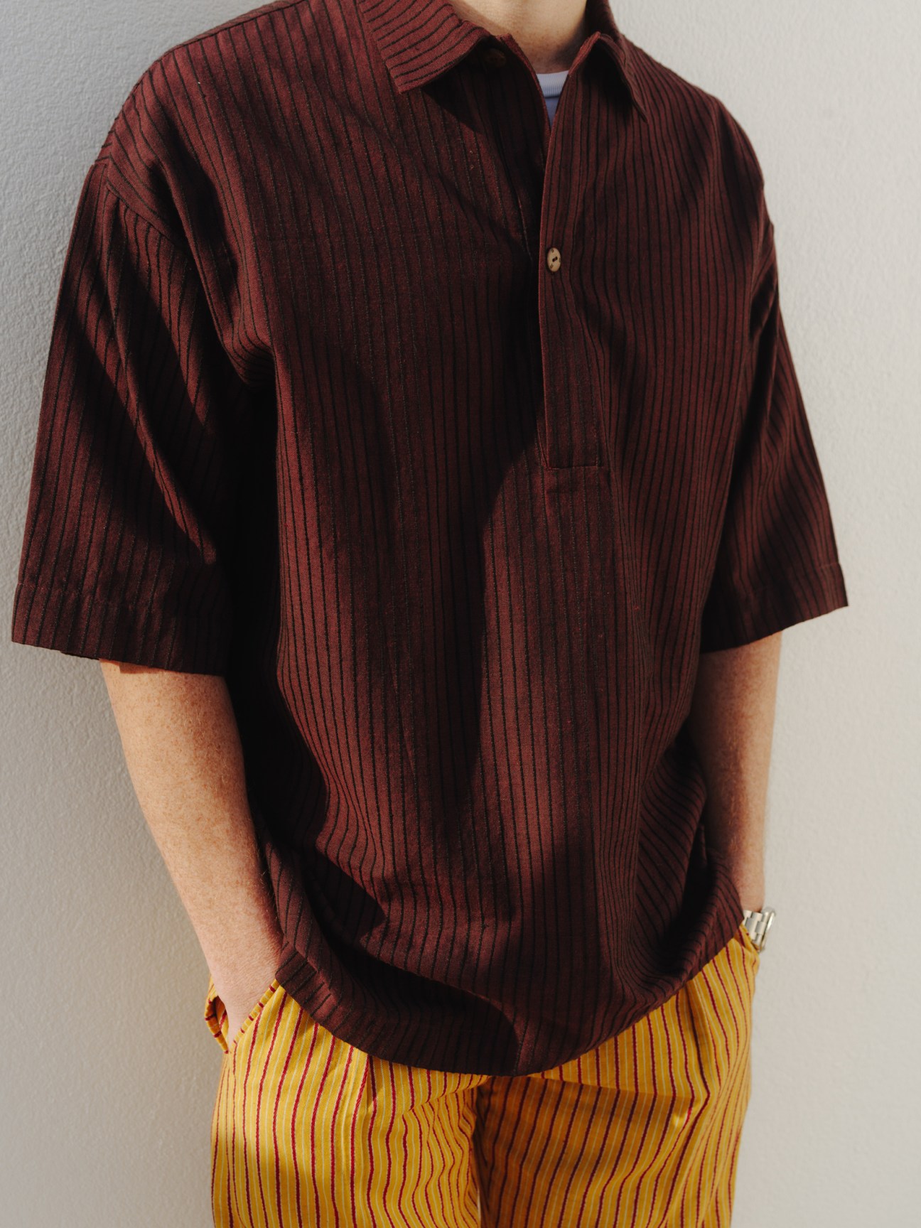 Man wearing burgundy striped short-sleeve shirt and yellow striped trousers.