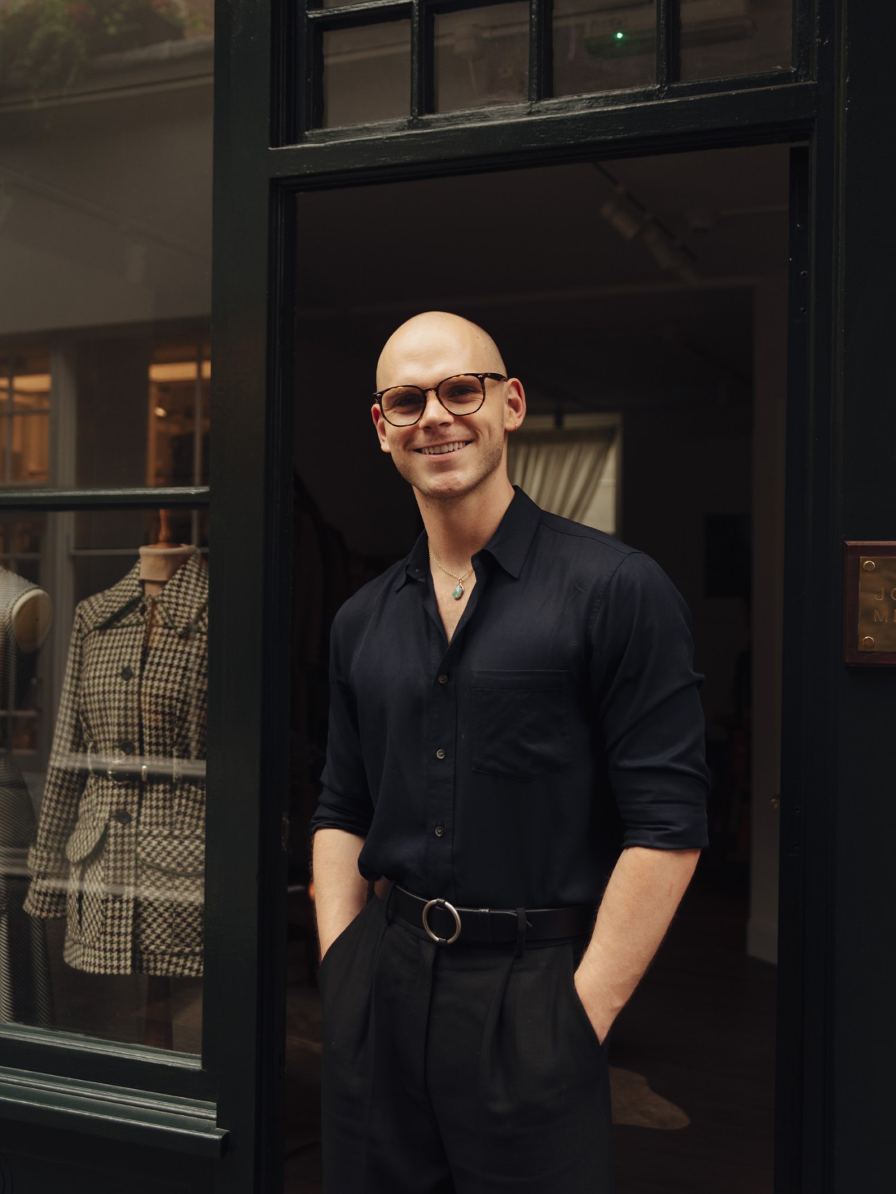 Man in black shirt and glasses standing in doorway of London home