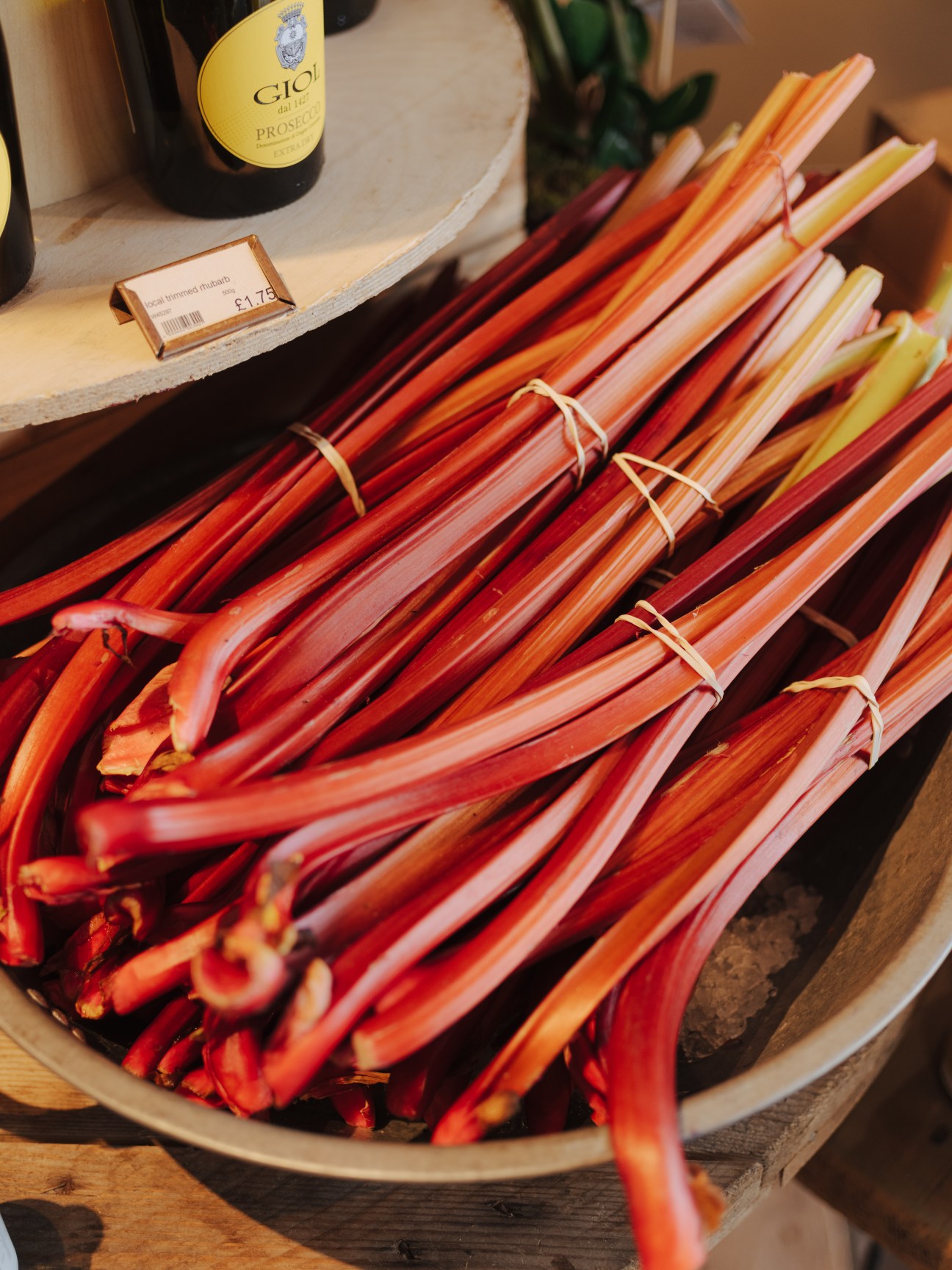 Bundles of fresh rhubarb with red and pink stalks tied with twine at Gloucester Services farm shop.