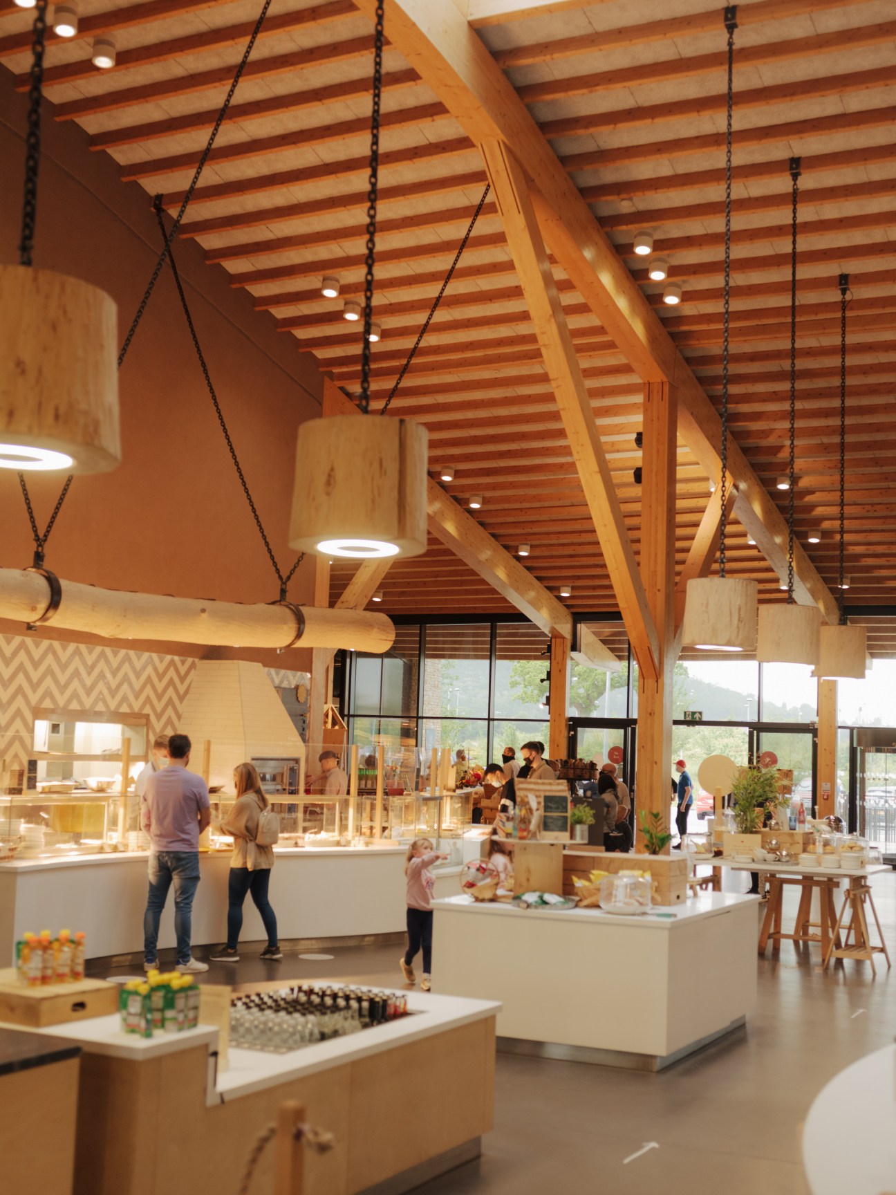 Interior of Gloucester Services showing wooden ceiling beams, pendant lights, and customers at service counters.