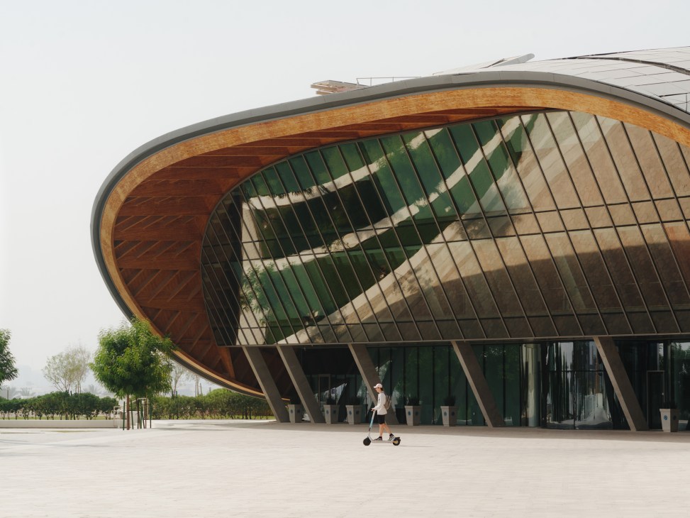 Modern curved building with wood and glass facade in Abu Dhabi's Masdar City, Mohamed bin Zayed University of Artificial Intelligence.