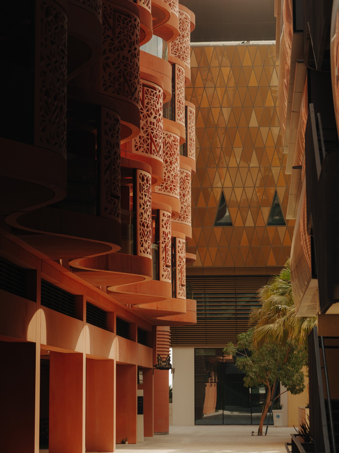 Modern campus courtyard with red-orange spiral staircase and ornate lattice screens echoing traditional Middle Eastern architecture.