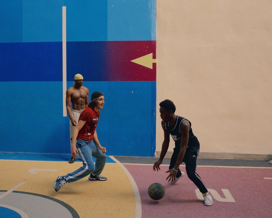 Young men playing basketball on colorful court with blue, yellow and pink surfaces