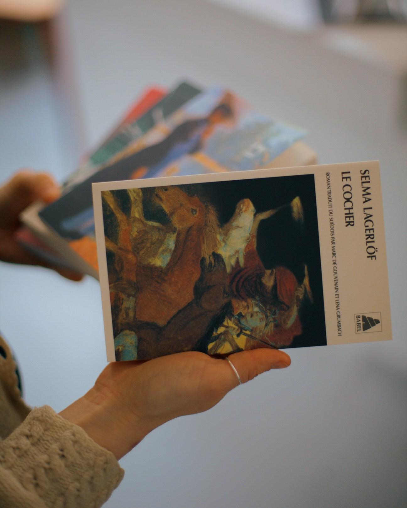 Hand holding Swedish book 'Selma Lagerlöf' by Le Cocher with artistic cover showing figures in earth tones