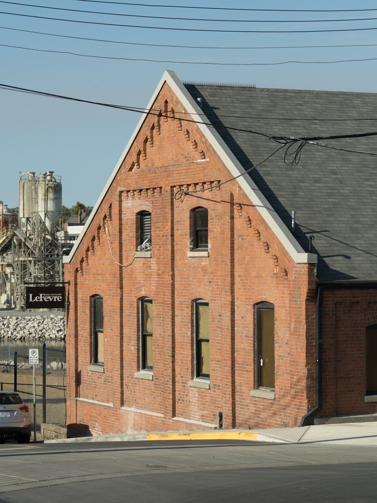 Red brick historic building with white trim and arched windows, housing Ecologyst's manufacturing facility in Victoria.