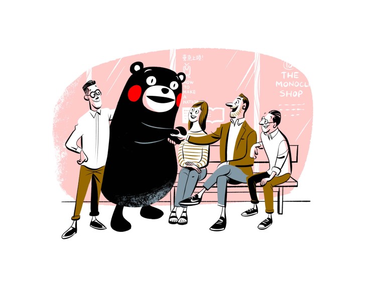 A cartoon illustration of Kumamon, the black bear mascot, cheerfully greeting a group of people outside a shop.
