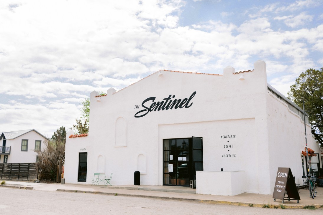 White building exterior with 'The Sentinel' signage and black entrance doors.