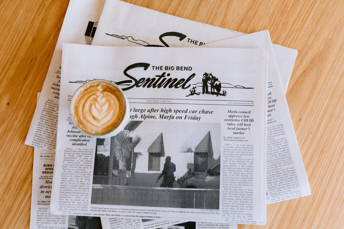 Coffee cup with latte art placed on The Big Bend Sentinel newspaper.