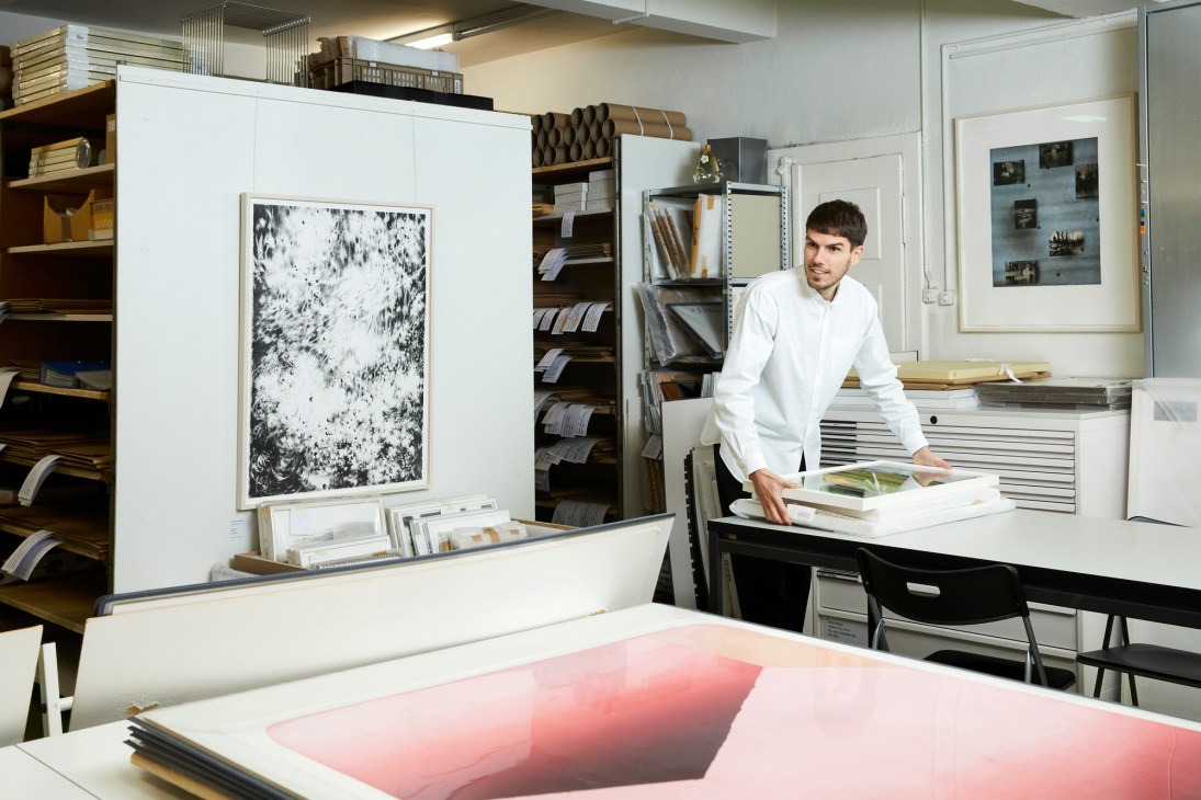 David Khalat standing in a gallery space with artwork displayed on white walls behind him