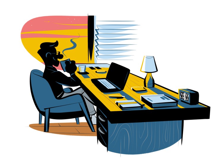 Person working at desk with laptop during late hours, with warm lighting and air conditioning visible