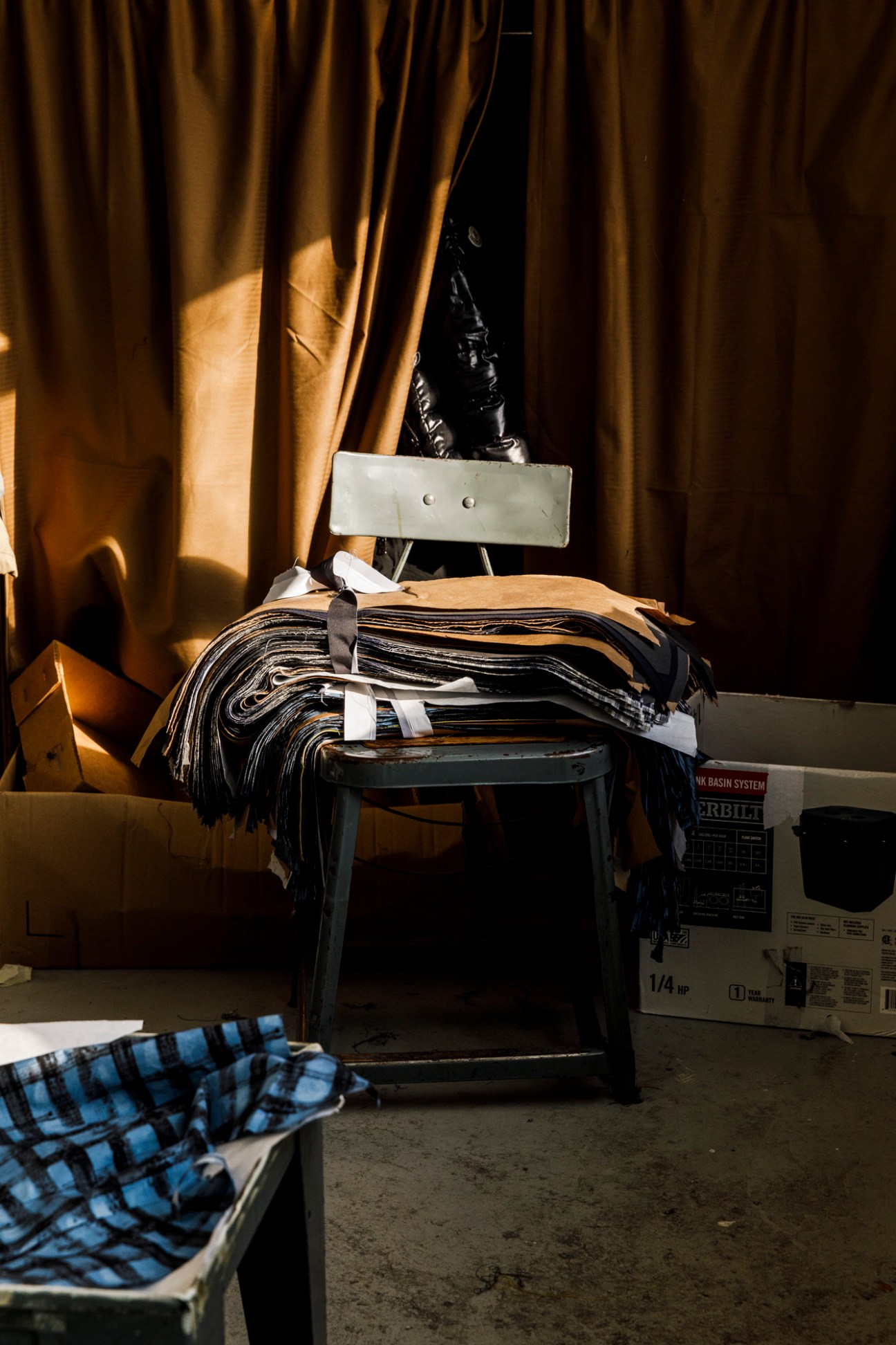 Stacks of fabric samples and materials piled on a chair in a workshop setting