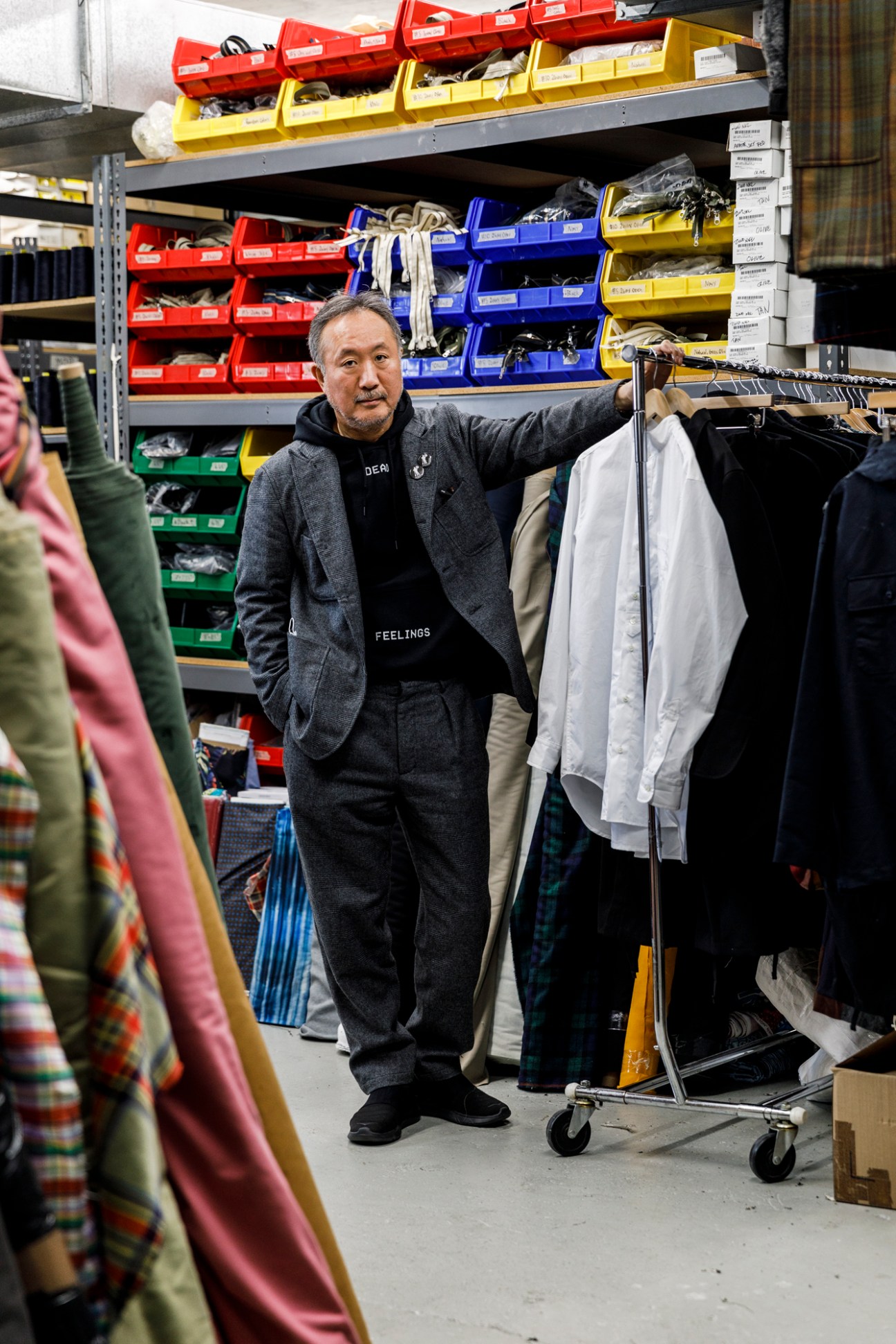 Daiki Suzuki standing in warehouse with shelving containing organized storage bins and hanging clothes