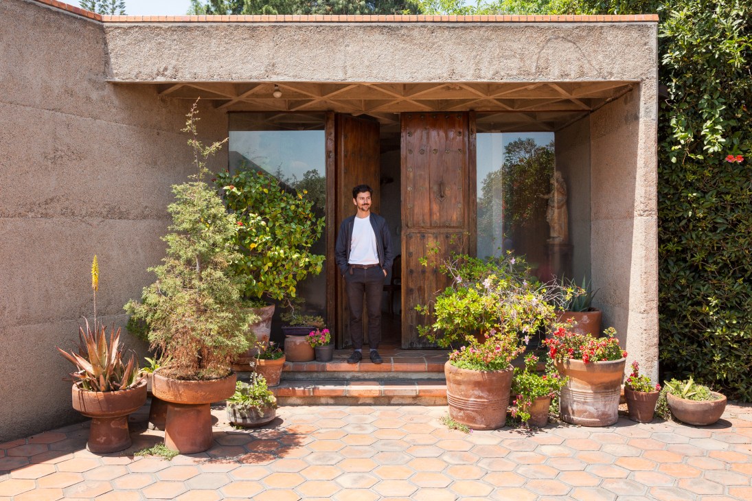 Carlos H Matos stands in the plant-laden entrance of his grandfather Ernesto Gallardo's modernist concrete home in San Jerónimo, Mexico City.