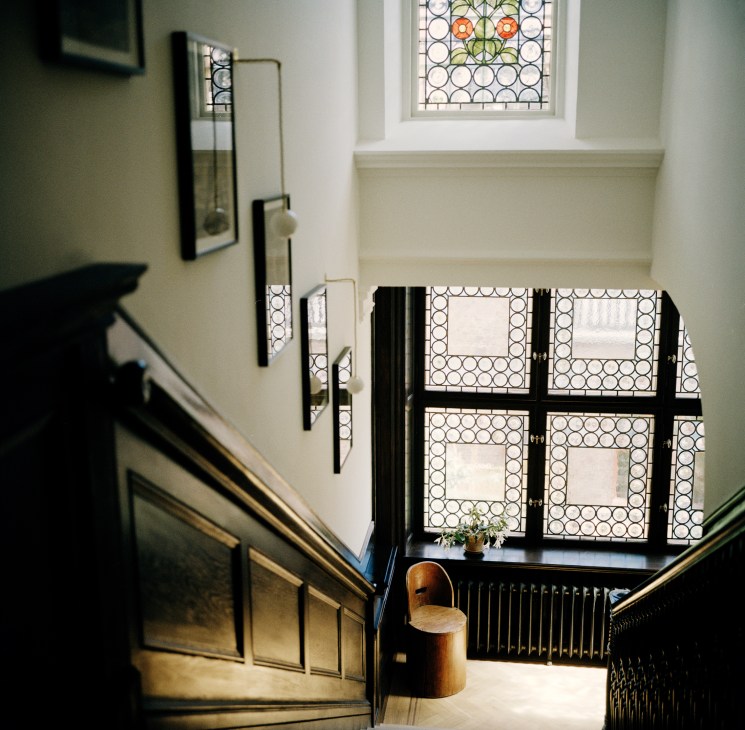 Elegant wooden staircase with original banister and modern pendant lighting from Michael Anastassiades