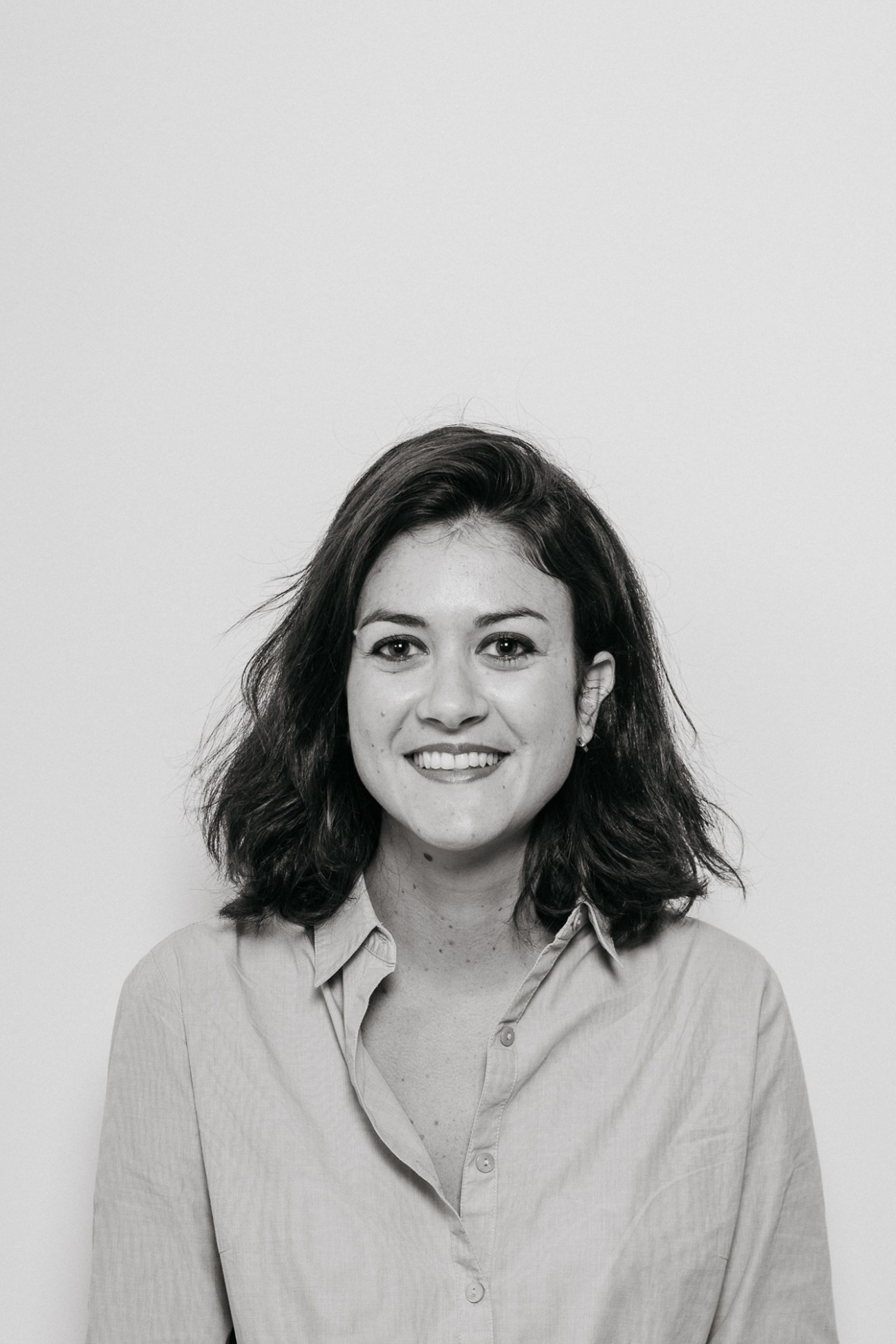 Black and white portrait of a woman with shoulder-length dark hair wearing a light-colored button-up shirt.