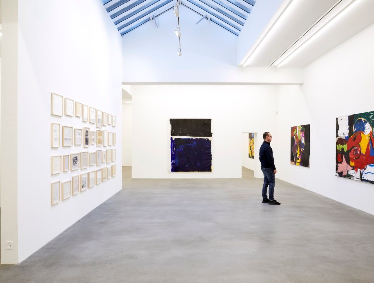 man standing at a gallery looking at a painting