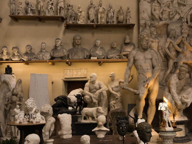 Room filled with classical sculpture reproductions including busts, reliefs and statues displayed on shelves and tables