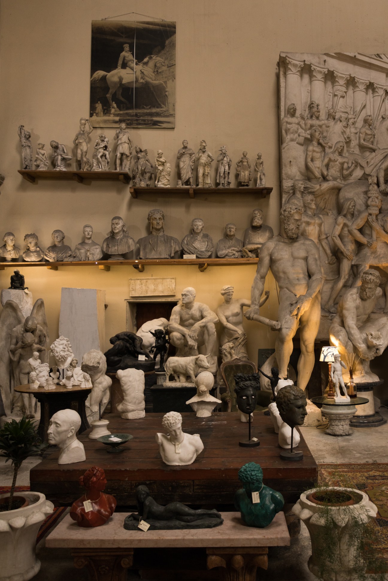 Room filled with classical sculpture reproductions including busts, reliefs and statues displayed on shelves and tables
