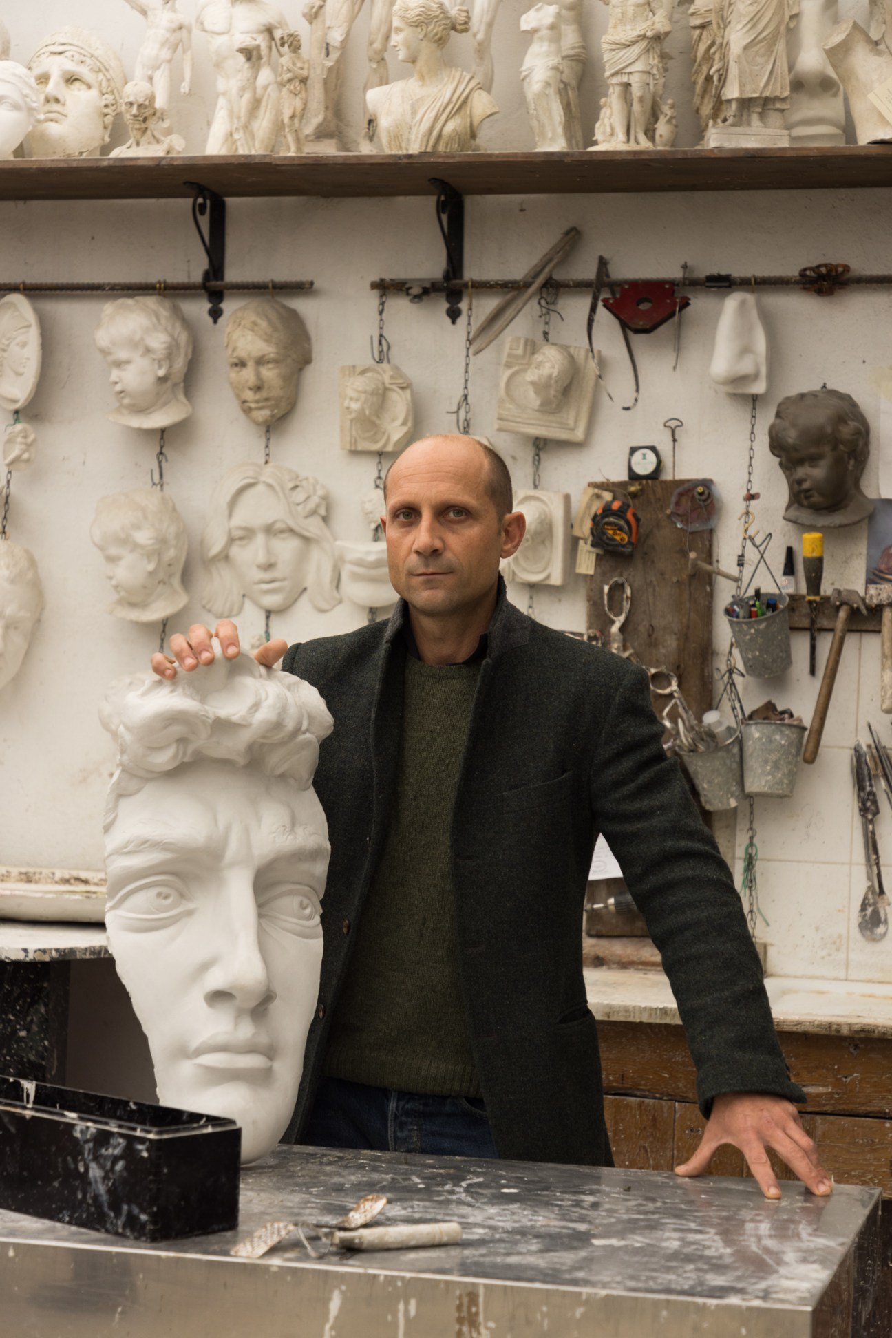 Owner Raffaello Romanelli stands in his sculpture workshop surrounded by plaster busts and sculpting tools