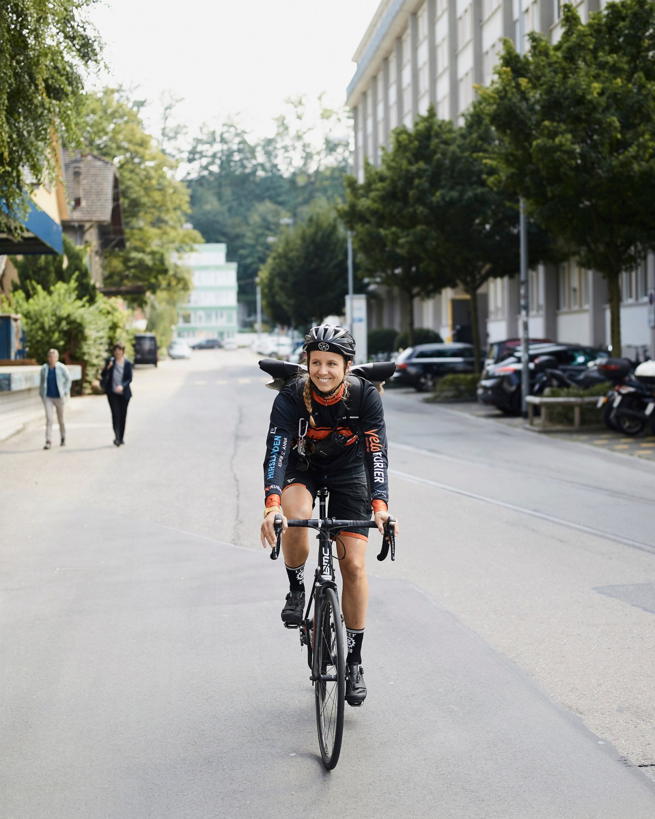Cyclist riding through Lucerne city street with historic buildings and trees
