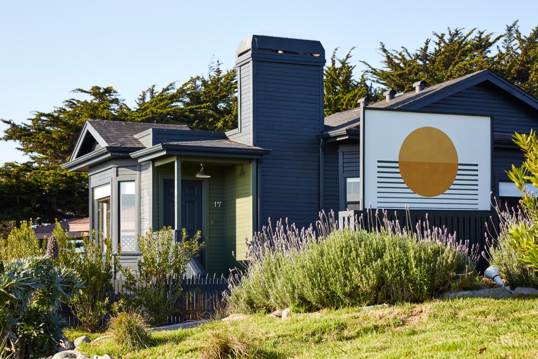 Modern hotel bungalows with dark blue and white exteriors facing coastal landscape.