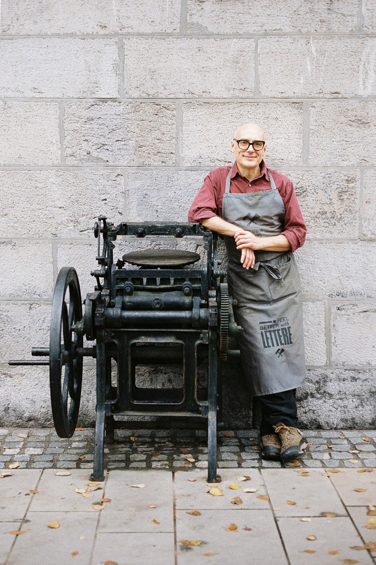 Marko Drpic operating a vintage letterpress machine in his workshop, surrounded by type cases