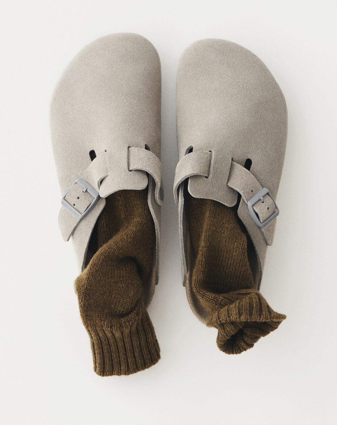 Grey socks and beige suede sandals with buckle straps worn on feet