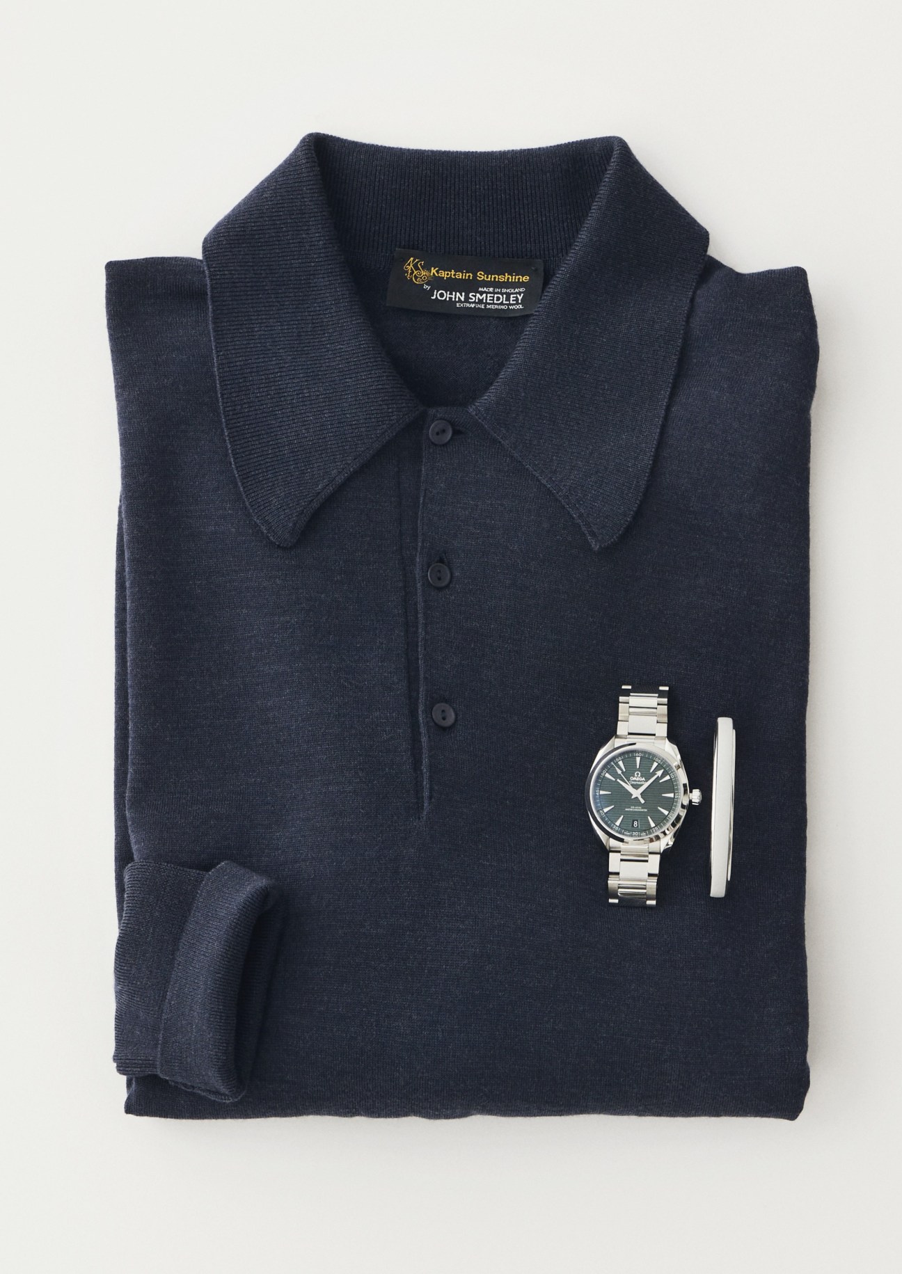 Navy knit polo shirt with collar and buttons displayed flat with Omega Seamaster watch and metal bracelet