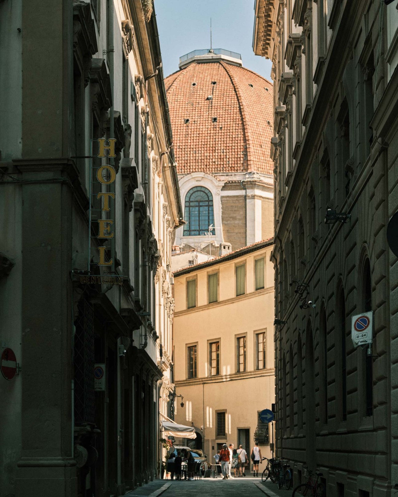 Narrow Florentine alley with terracotta dome of cathedral visible between historic buildings.